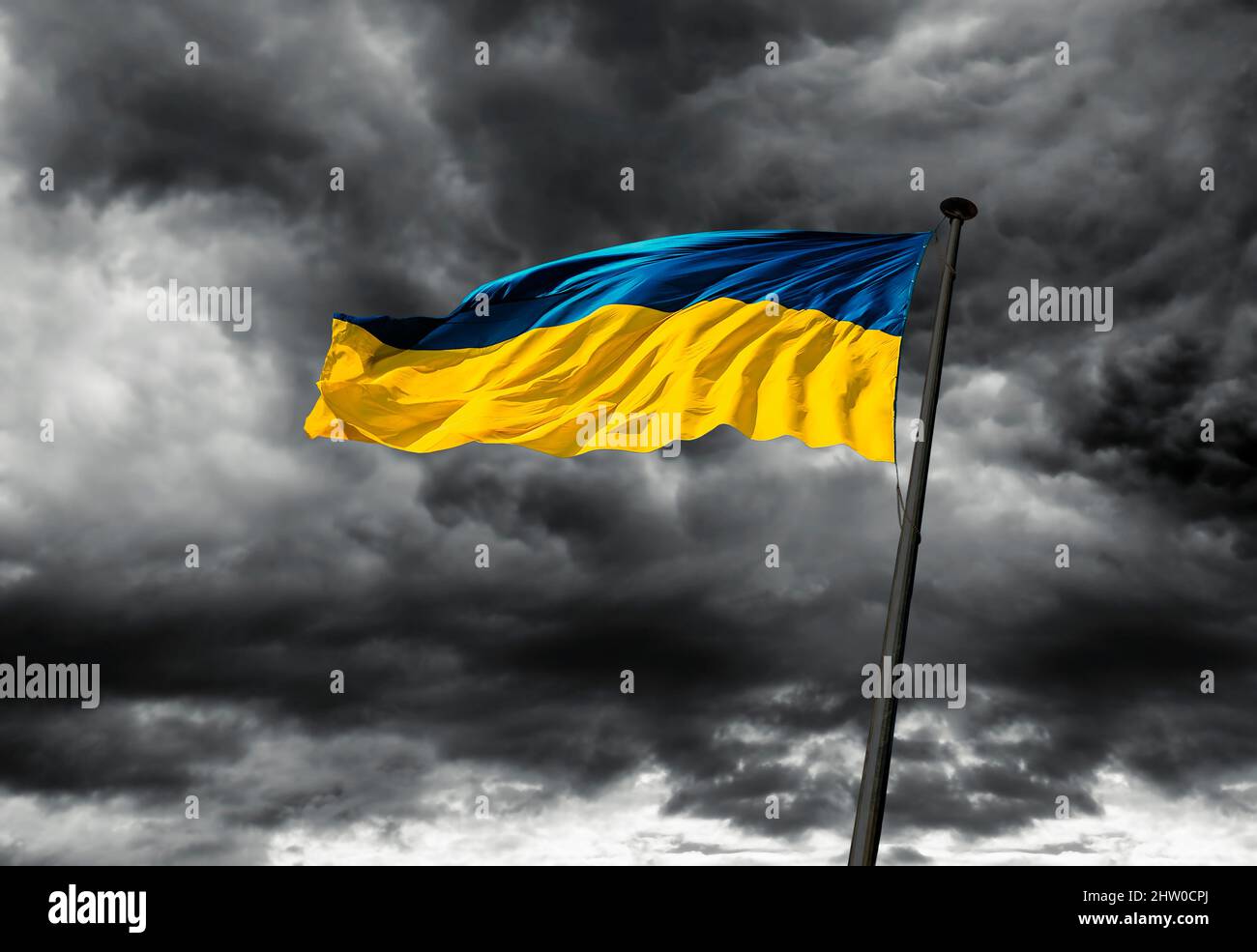 Eine ukrainische Flagge flattert im Wind gegen einen dunklen bewölkten Himmel. Stockfoto