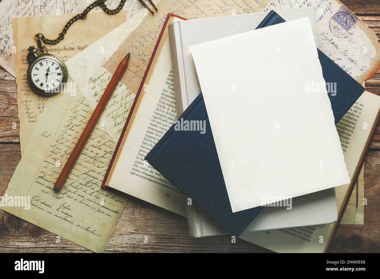 Weißes Schreibblatt mit Platz zum Kopieren auf Büchern und Postkarten neben einer alten Uhr und einem Bleistift Stockfoto