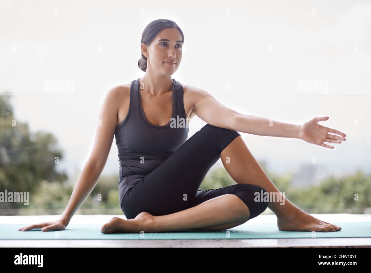 Beginnen Sie Ihren Tag mit einer guten Yoga-Sitzung. Ganzkörperaufnahme einer jungen Frau, die Yoga macht. Stockfoto