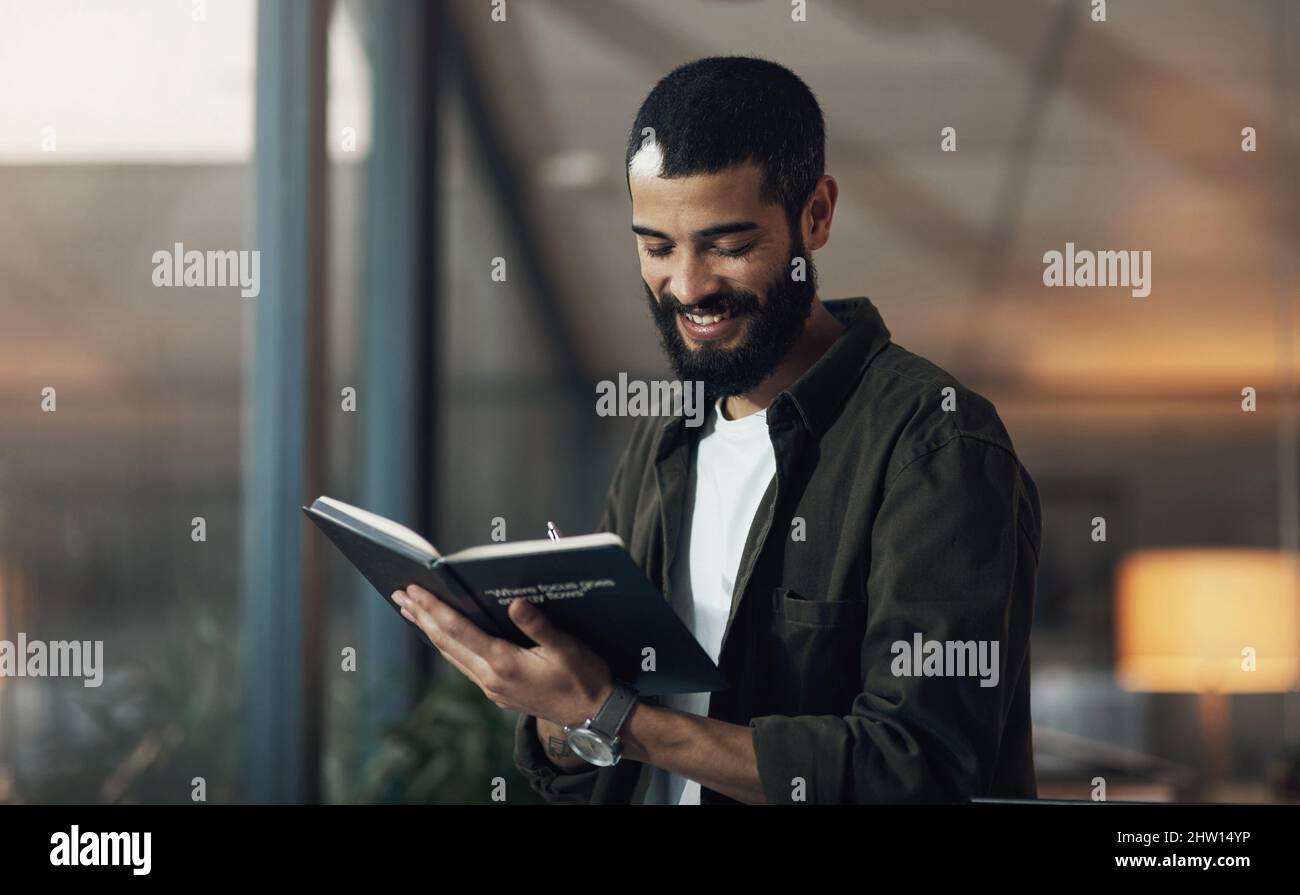 Eine weitere Aufgabe wurde erledigt und abgestaubt. Aufnahme eines jungen Geschäftsmannes, der in einem Notebook in einem modernen Büro in einer späten Nacht schrieb. Stockfoto