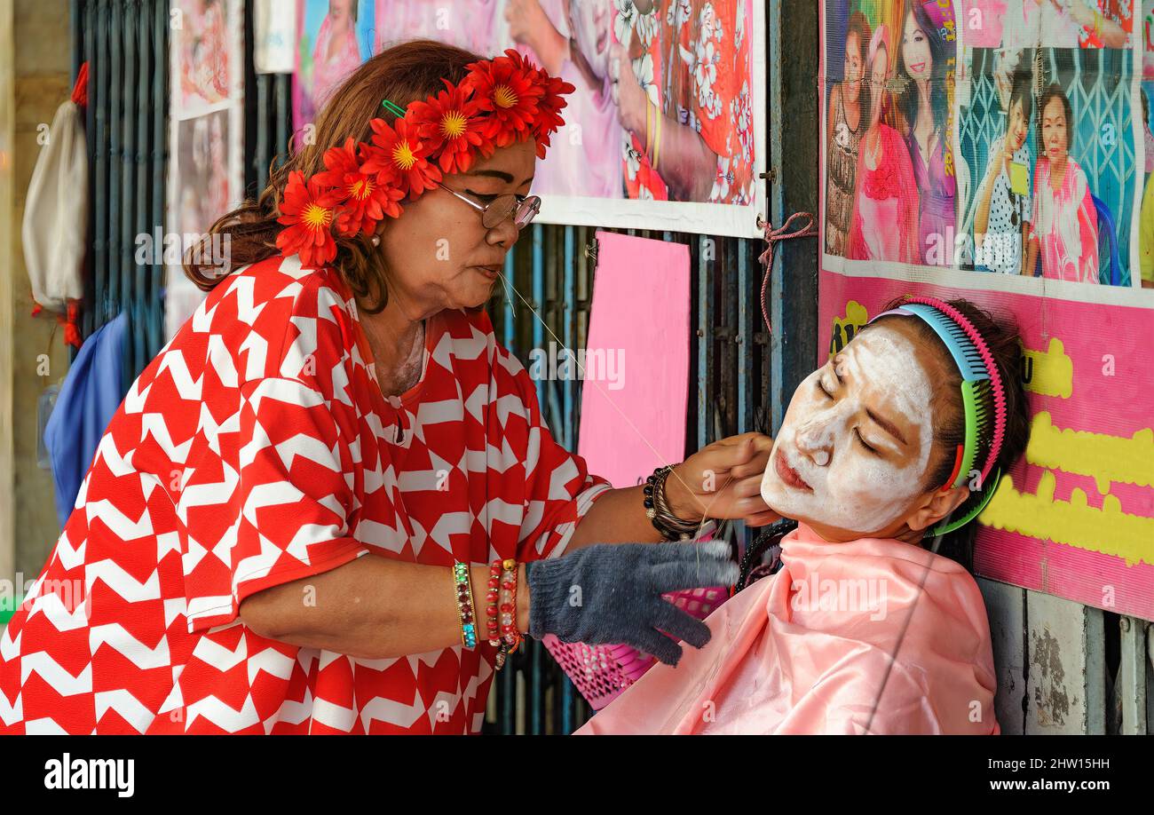 Chinatown, Bangkok – 14. Nov 2020: Alte chinesische Methode, Gesichtshaare mit zwei Fäden zu entfernen, um sie zu quetschen und zu ziehen. Stockfoto
