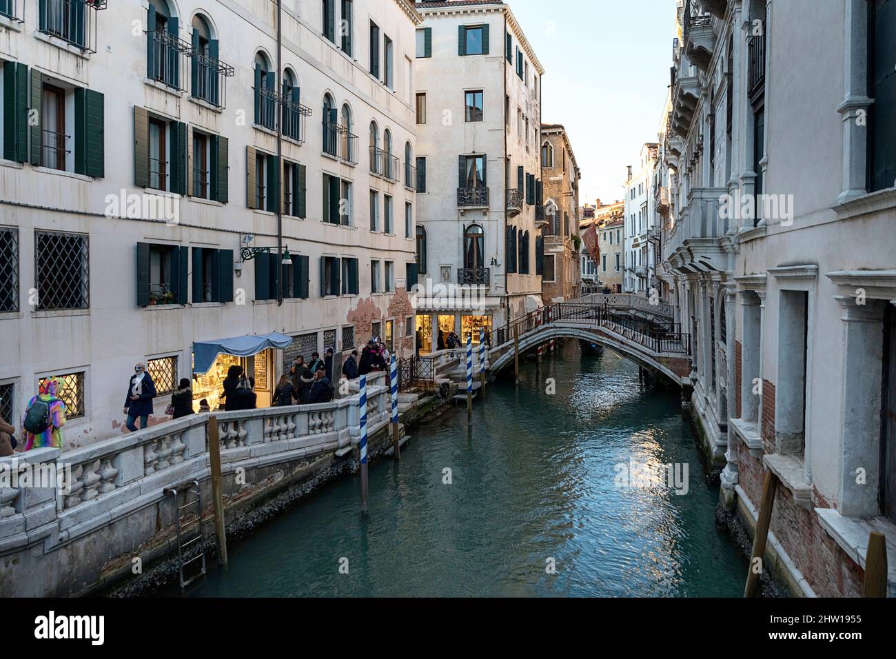 Einheimische und Touristen auf einer Straße in der Nähe eines Wasserkanals in Venedig an einem Karnevalstag an einem schönen sonnigen Tag, Venedig, Italien Stockfoto