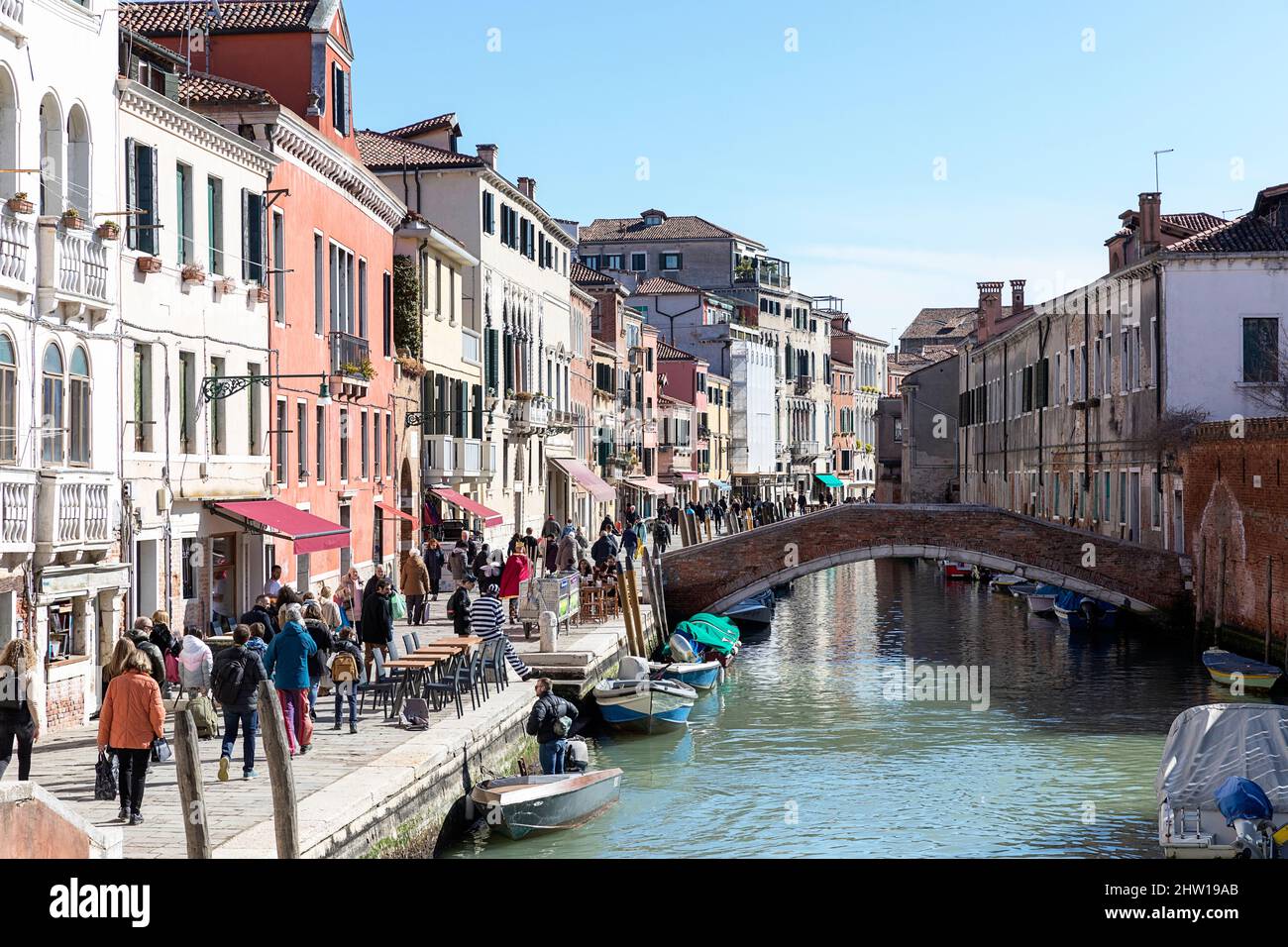 Einheimische und Touristen auf einer Straße in der Nähe eines Wasserkanals in Venedig an einem Karnevalstag an einem schönen sonnigen Tag, Venedig, Italien Stockfoto