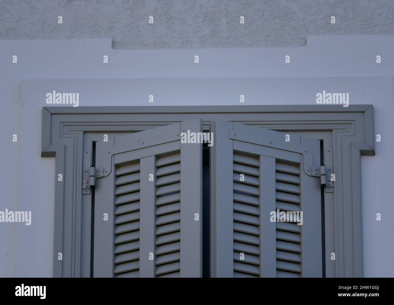 Neoklassizistisches Haus hellgraues Holzfenster mit Fensterläden an einer weißgetünchten Wand in Nafplio, Griechenland. Stockfoto