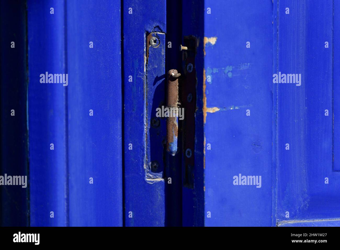 Altes Landhaus ultramarinblau Holztür mit abgebrochenem Lack und einem rostigen Scharnier in Nafplio, Griechenland. Stockfoto