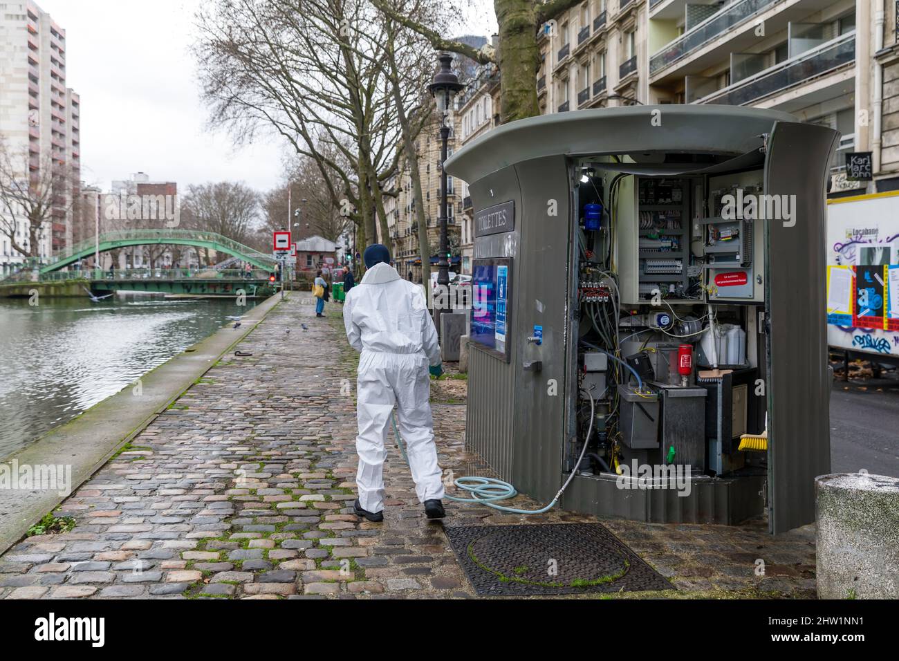 Frankreich, Paris, Kanal Saint Martin, Quai de Valmy, ein Mann unterhält eine öffentliche JC Decaux Toilette Stockfoto