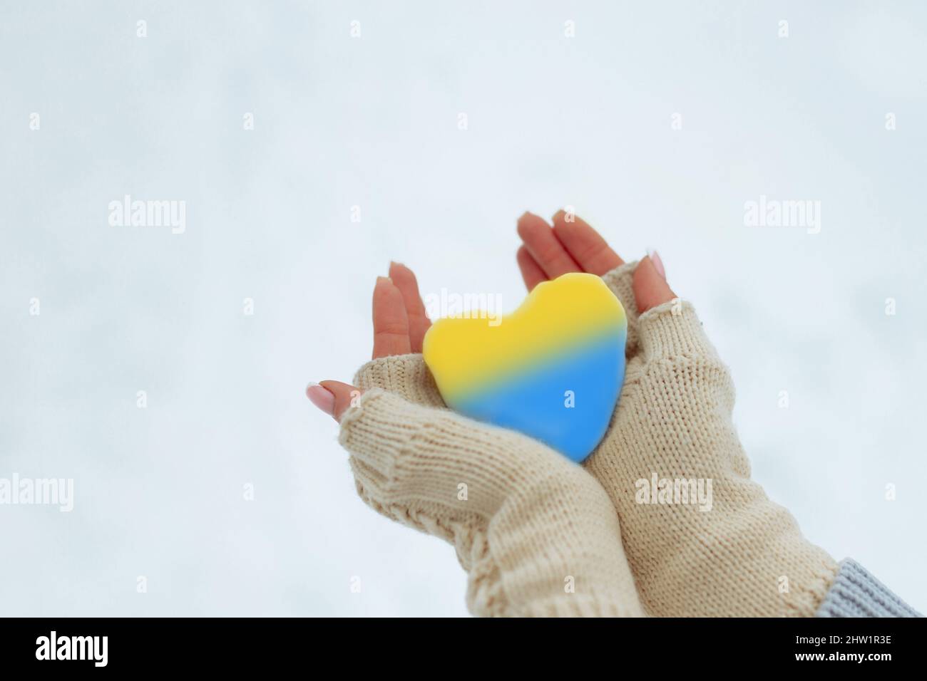 Kein Krieg. Februar der Beginn des Krieges in der Ukraine das Mädchen hält ein Herz von pathetischer blauer Farbe in den Händen. Frieden in der Ukraine Stockfoto