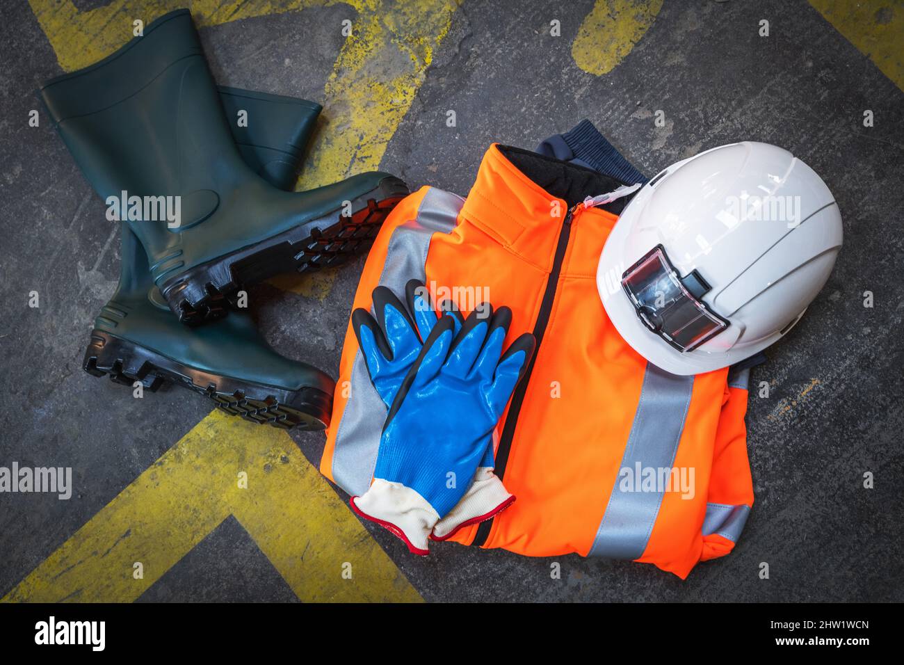 Professionelle Schutzkleidung für Baustellen und Gebäude auf einem betonierten Hintergrund mit Verkehrszeichen. Bau, Industrie und Arbeiter PR Stockfoto