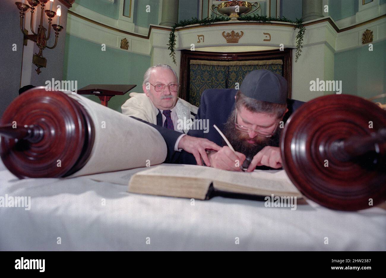 Der Oberrabbiner Jonathan Sacks war Ehrengast für die Aufnahme der letzten Briefe in eine neue Sefer-Torah in der Synagoge der hebräischen Kongregation Singers Hill am Sonntag, dem 15. März 1998. Mitglieder der Gemeinde sowie der Oberrabbiner fügten jeweils einen einzigen Brief hinzu. Rev Uzi Brown ist der Schreiber. Stockfoto