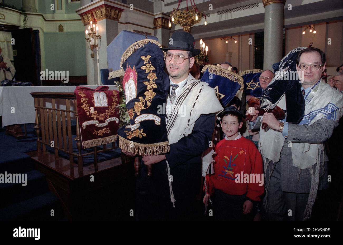 Die neue Sefer Tora wird um die Synagoge getragen, damit die Gemeinde ihre Achtung zollt. Der Oberrabbiner Jonathan Sacks war Ehrengast für die Aufnahme der letzten Briefe in eine neue Sefer-Torah in der Synagoge der hebräischen Kongregation Singers Hill am Sonntag, dem 15. März 1998. Mitglieder der Gemeinde sowie der Oberrabbiner fügten jeweils einen einzigen Brief hinzu. Stockfoto