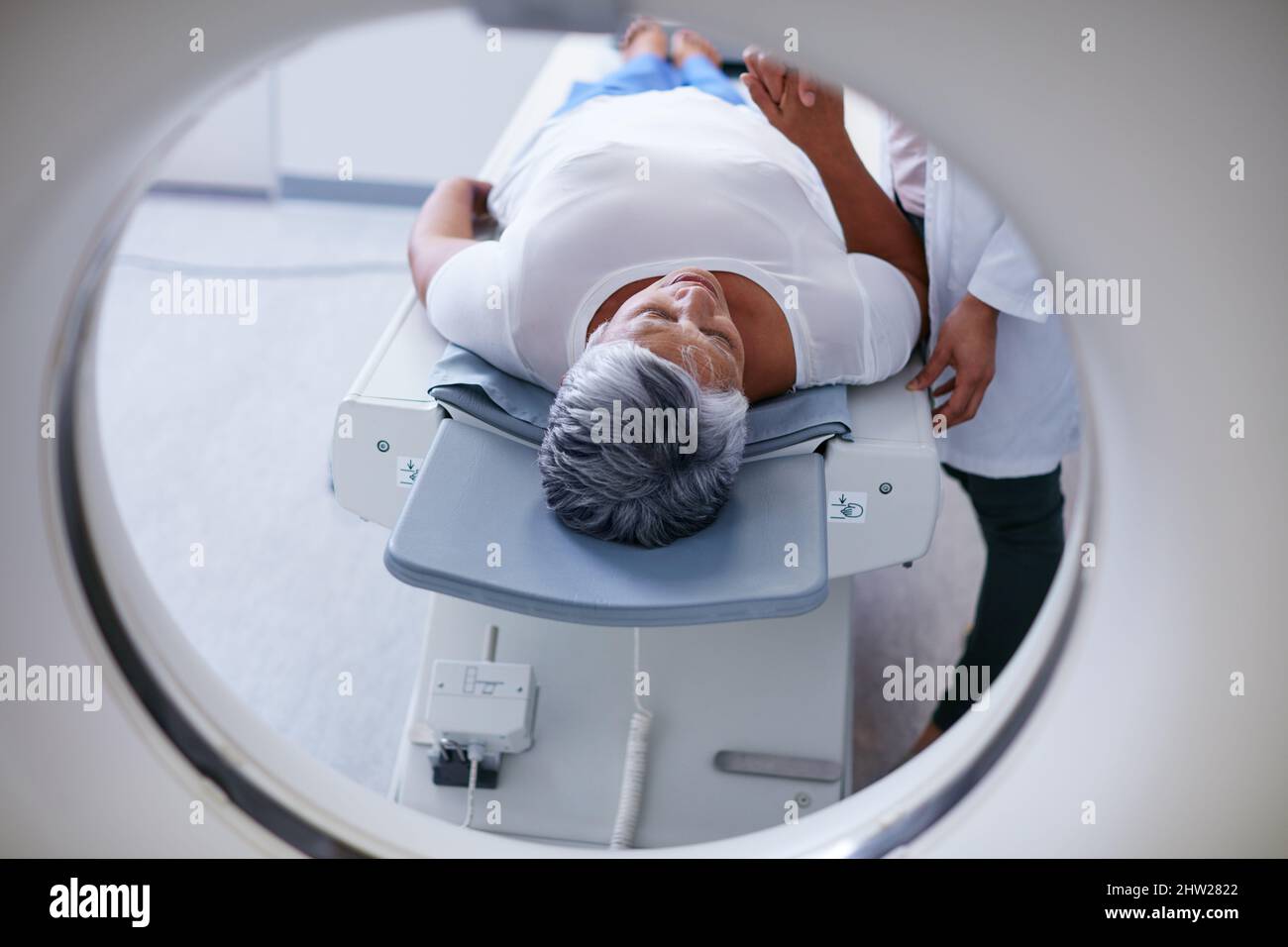 Scanvorgang wird vorbereitet. Aufnahme einer älteren Frau, die zuvor von einem Arzt getröstet wurde, und einer MRT-Untersuchung. Stockfoto