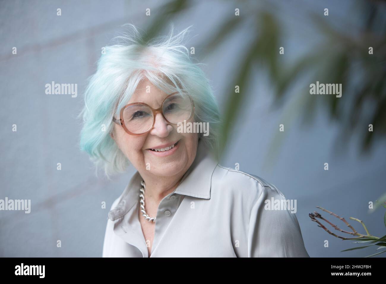 Porträt einer modernen älteren Frau, die mit einem Lächeln im Freien auf die Kamera schaut Stockfoto