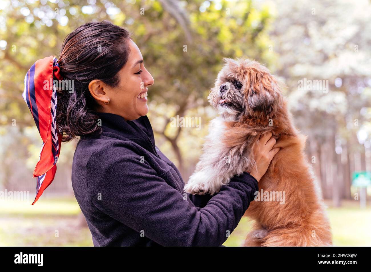 Nette junge Frau umarmt ihren kleinen Welpen. Liebe zwischen Besitzer und Hund. Außenfoto im Park, selektiver Fokus. Lifestyle-Konzept Stockfoto