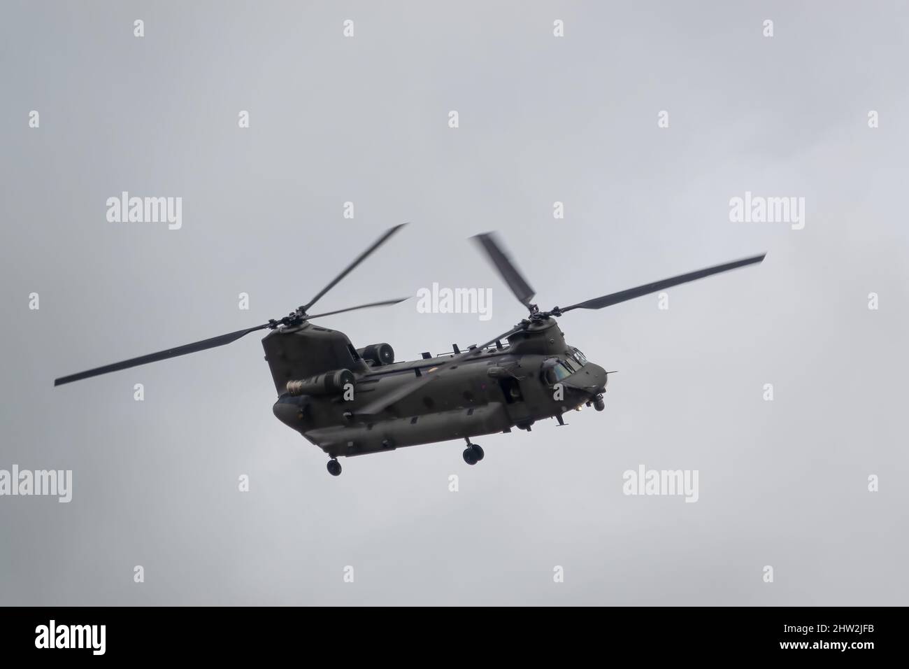RAF Chinook Tandem-Rotor CH-47 Hubschrauber fliegt schnell und tief in einem wolkigen blauen grauen Himmel auf einer militärischen Kampfübung, Wilts UK Stockfoto