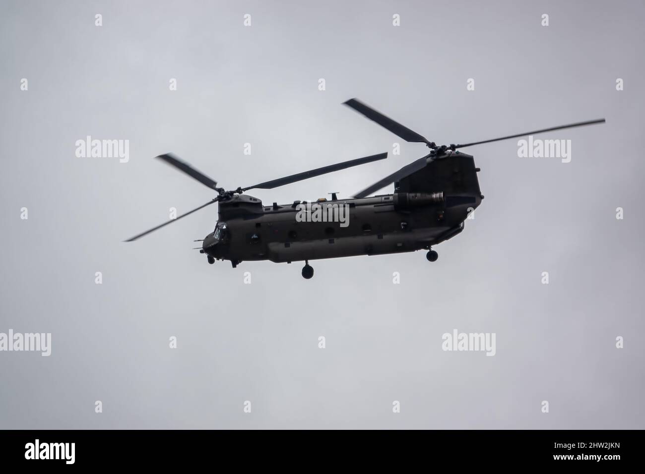 RAF Chinook Tandem-Rotor CH-47 Hubschrauber fliegt schnell und tief in einem wolkigen blauen grauen Himmel auf einer militärischen Kampfübung, Wilts UK Stockfoto