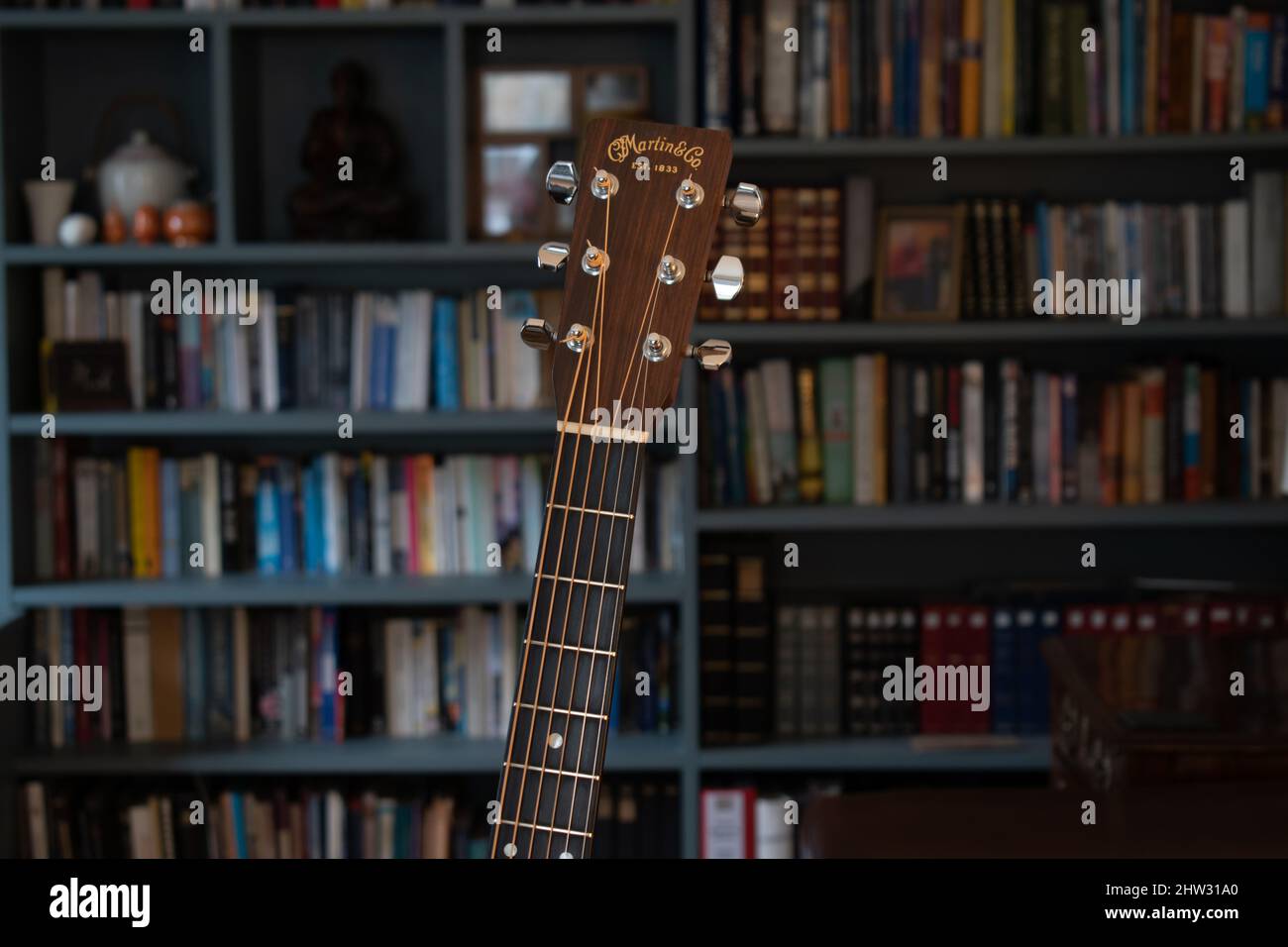 Eine alte Martin D28 Gitarre sitzt in einem sanft beleuchteten Raum. Warme Farben und Ambiente füllen den Rahmen. Entspannte Atmosphäre.scharfer Fokus mit einem weichen warmen Hintergrund Stockfoto