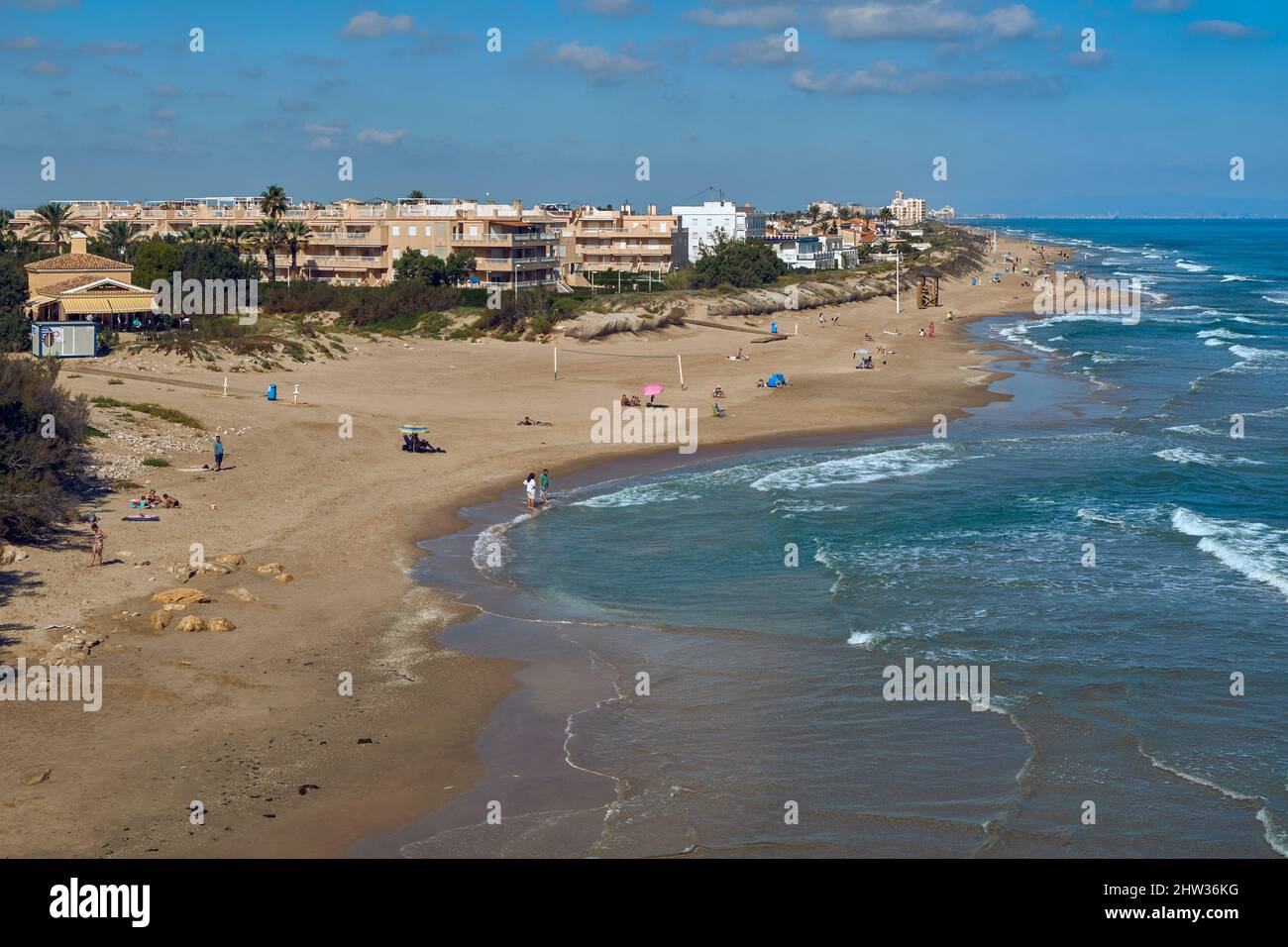 Sonnenbaden mit Sonnenschirmen im Sand und Baden am Strand von Dossel in der Küstenstadt Cullera Provinz Valencia, Spanien, Europa Stockfoto