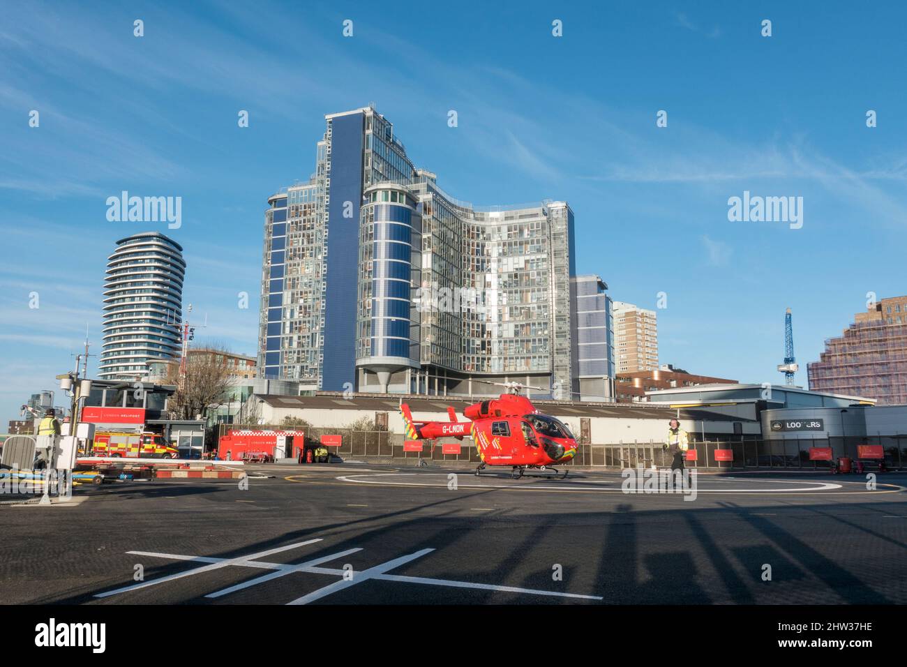 Ein Hubschrauber der Londoner Air Ambulance landet im Londoner Heliport, Battersea, London, Großbritannien. Hinter dem Hubschrauberlandeplatz erhebt sich die Entwicklung von Falcon Wharf. Stockfoto