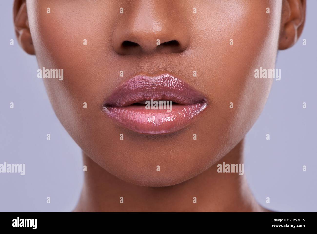 Luziöse Lippen. Ausgeschnittene Aufnahme einer jungen Frau vor einem violetten Hintergrund. Stockfoto