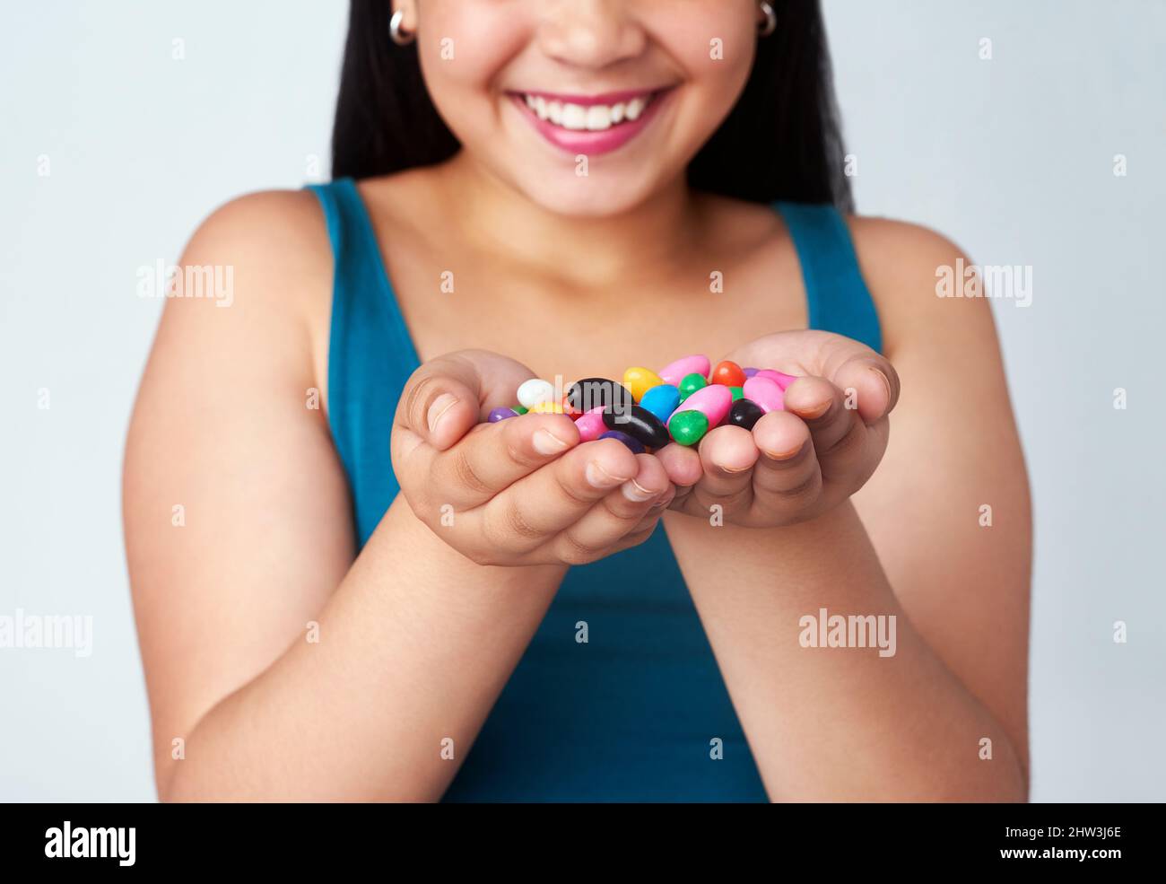 Was ist Ihr Lieblingsgeschmack. Studio-Aufnahme eines niedlichen jungen Mädchens mit einer Handvoll farbenfroher Gelee-Bohnen. Stockfoto