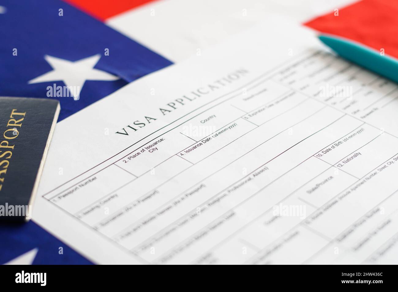 Frau, die das Antragsformular für das Visum ausgefüllt hat. Amerikanische Flagge auf dem Hintergrund. Einwanderung in die USA. Stockfoto