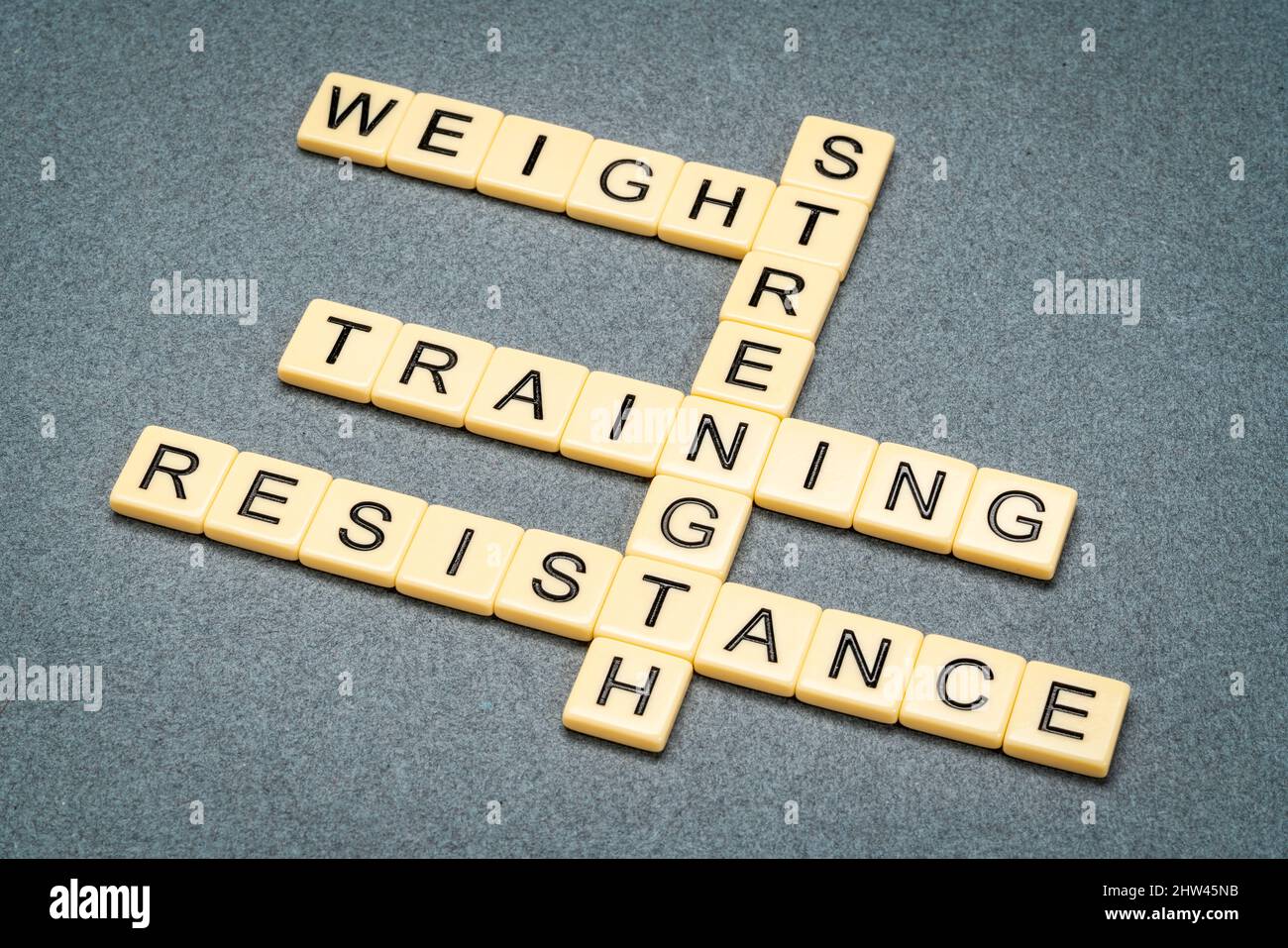 Kraft, Gewicht und Widerstand Training Kreuzworträtsel in Elfenbein Buchstaben Fliesen gegen texturiertes Papier, Fitness-Konzept Stockfoto
