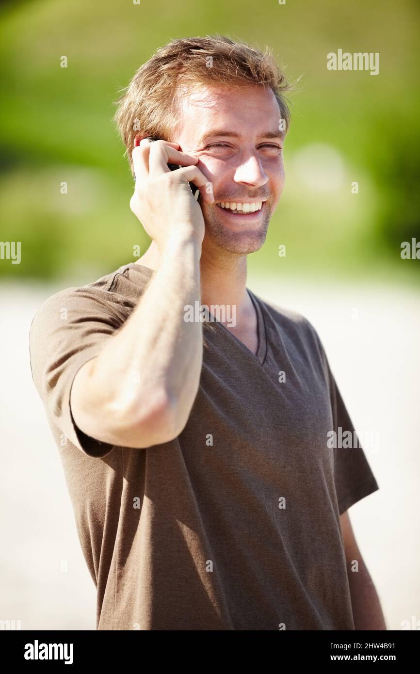 Es ist toll, von Ihnen zu hören. Ein hübscher junger Mann, der sich am Handy unterhielt und lachte. Stockfoto