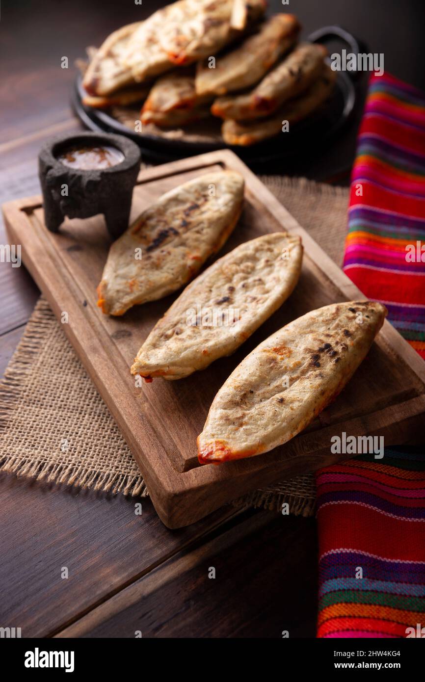 Tlakoyos. Mexikanisches pre-hispanisches Gericht aus Maismehl-Patty, gefüllt mit Chicharron-Prensado (gepresste Schweinekälte). Beliebte Straßengerichte in Mexiko. Stockfoto