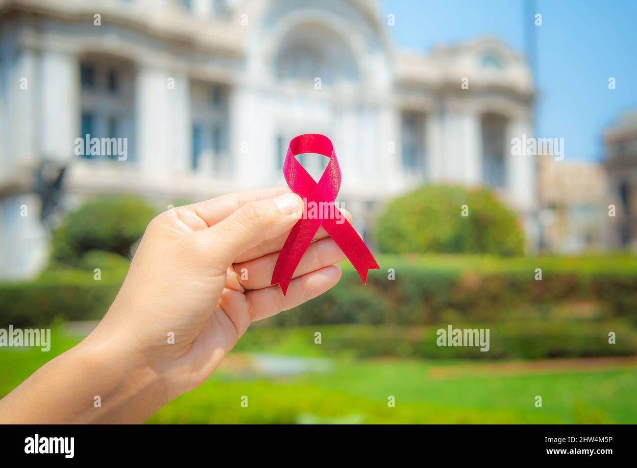 Frau Hände halten roten Band ist auf der Straße und Hintergrund ist nicht fokussiert. Konzept der Medizin, Kampagne zum Welt-AIDS-Tag. Stockfoto