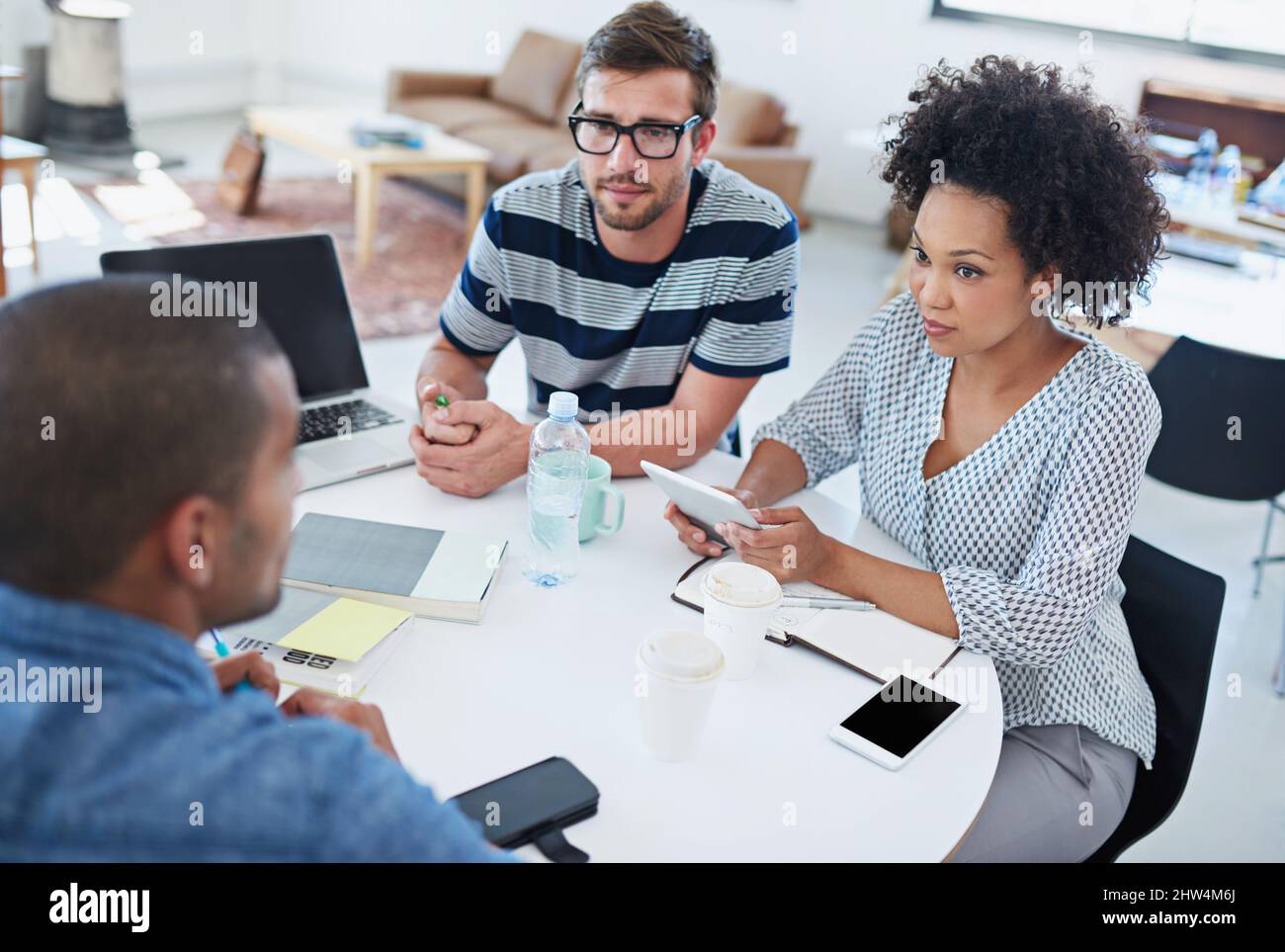 Teamdynamik. Aufnahme von Kollegen, die über ein digitales Tablet reden. Stockfoto