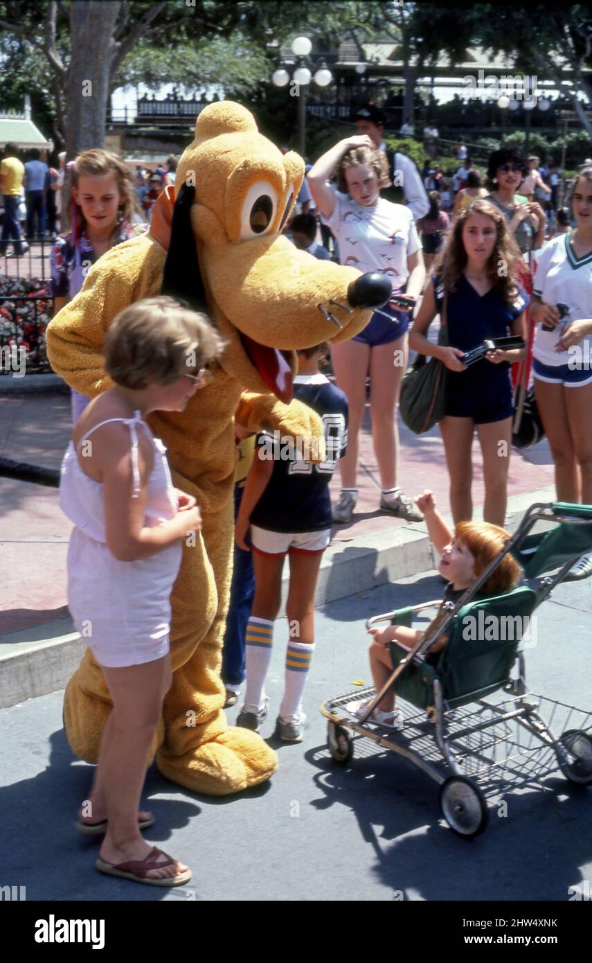 Besucher von Disneyland reagieren auf den kostümierten Charakter von Pluto Pup an der Main Street in Anaheim, CA Stockfoto