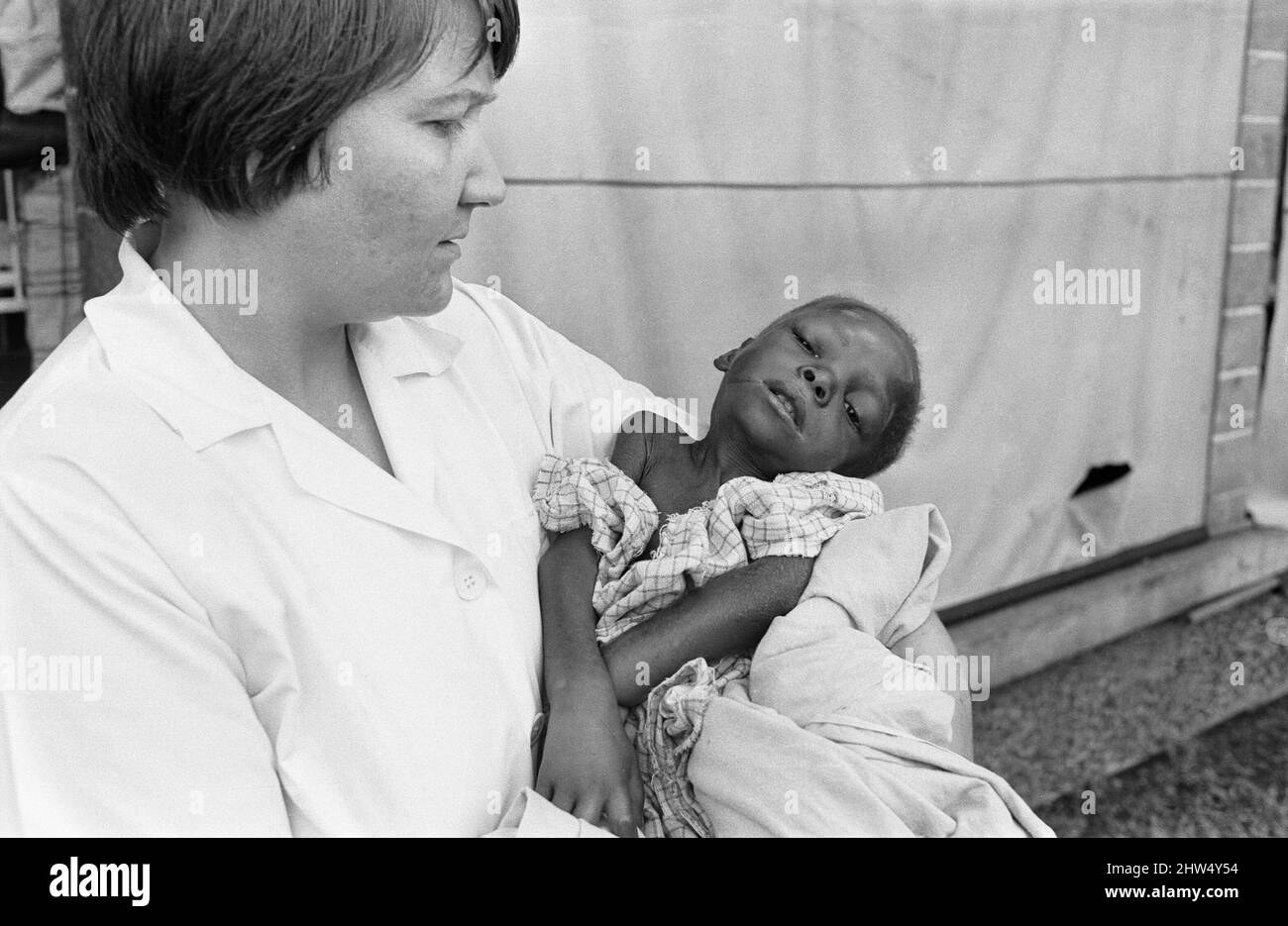 Ein Baby stirbt an Unterernährung in den Armen einer britischen Krankenschwester im Queen Elizabeth Hospital, Umuahia, nur eines der geschätzten ein bis zwei Millionen Opfer des Biafran-Krieges. 11.. Juni 1968The der nigerianische Bürgerkrieg, auch bekannt als Biafraner Krieg, dauerte zweieinhalb Jahre, vom 6. Juli 1967 bis zum 15. Januar 1970, und wurde gekämpft, um der Abspaltung von Biafra von Nigeria entgegenzuwirken. Die indigenen Igbo-Bewohner von Biafra fühlten sich nach der Unabhängigkeit von Großbritannien nicht mehr mit der nordeuropäischen Bundesregierung koexistieren können. Politische, wirtschaftliche, ethnische, kulturelle und religiöse Spannungen finden ihren Abschluss Stockfoto