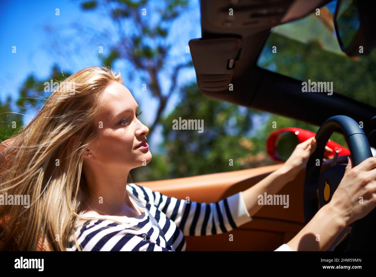 Ich habe den Bedarf an Geschwindigkeit. Aufnahme einer jungen Frau, die in einem Sportwagen fährt. Stockfoto