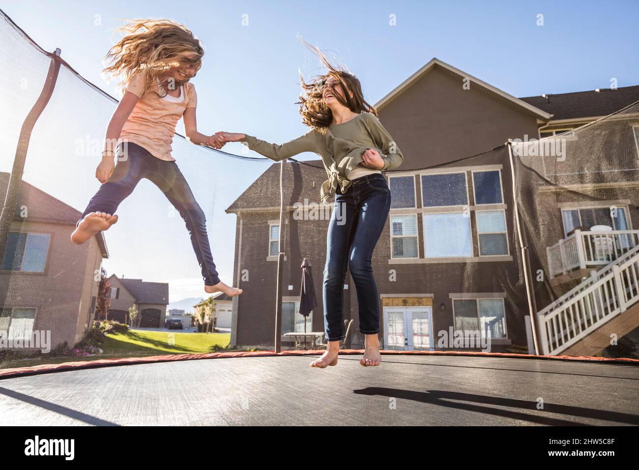 Mädchen (10-11, 12-13) springen auf dem Trampolin vor dem Haus Stockfoto