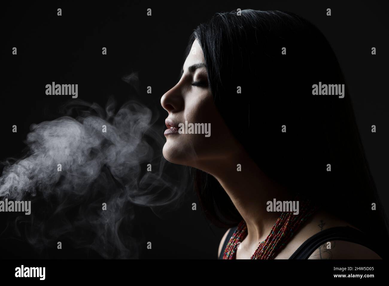 Profil der Frau mit Rauch vor schwarzem Hintergrund Stockfoto