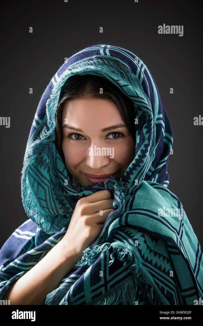 Studioporträt einer lächelnden Frau mit Schal auf dem Kopf Stockfoto