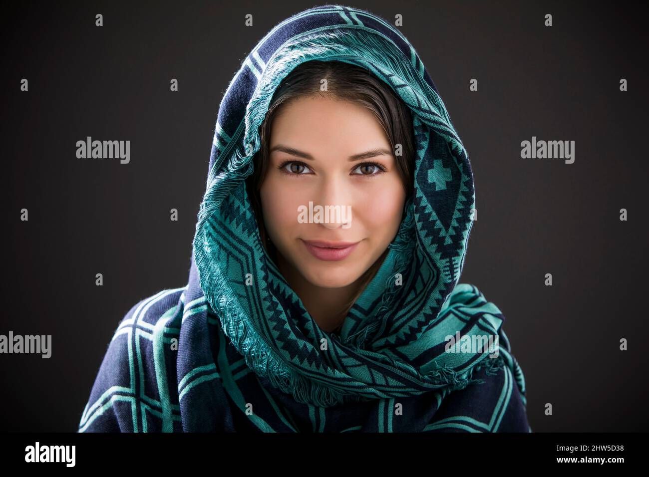 Studioporträt einer lächelnden Frau mit Schal auf dem Kopf Stockfoto