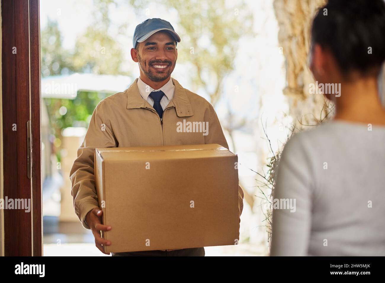 Kundenbeziehungen sind seine Stärke. Aufnahme eines Lieferers, der eine Lieferung an einen Kunden zu Hause anstellt. Stockfoto