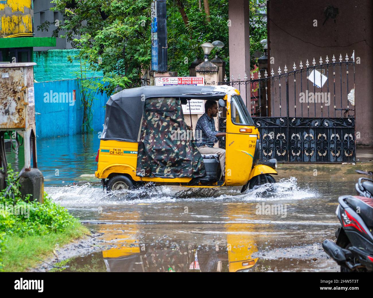 Eine Auto-Rikscha, die während der heftigen Monsunregen in Chennai auf einer wasserumgeloggten Straße fährt. Stockfoto
