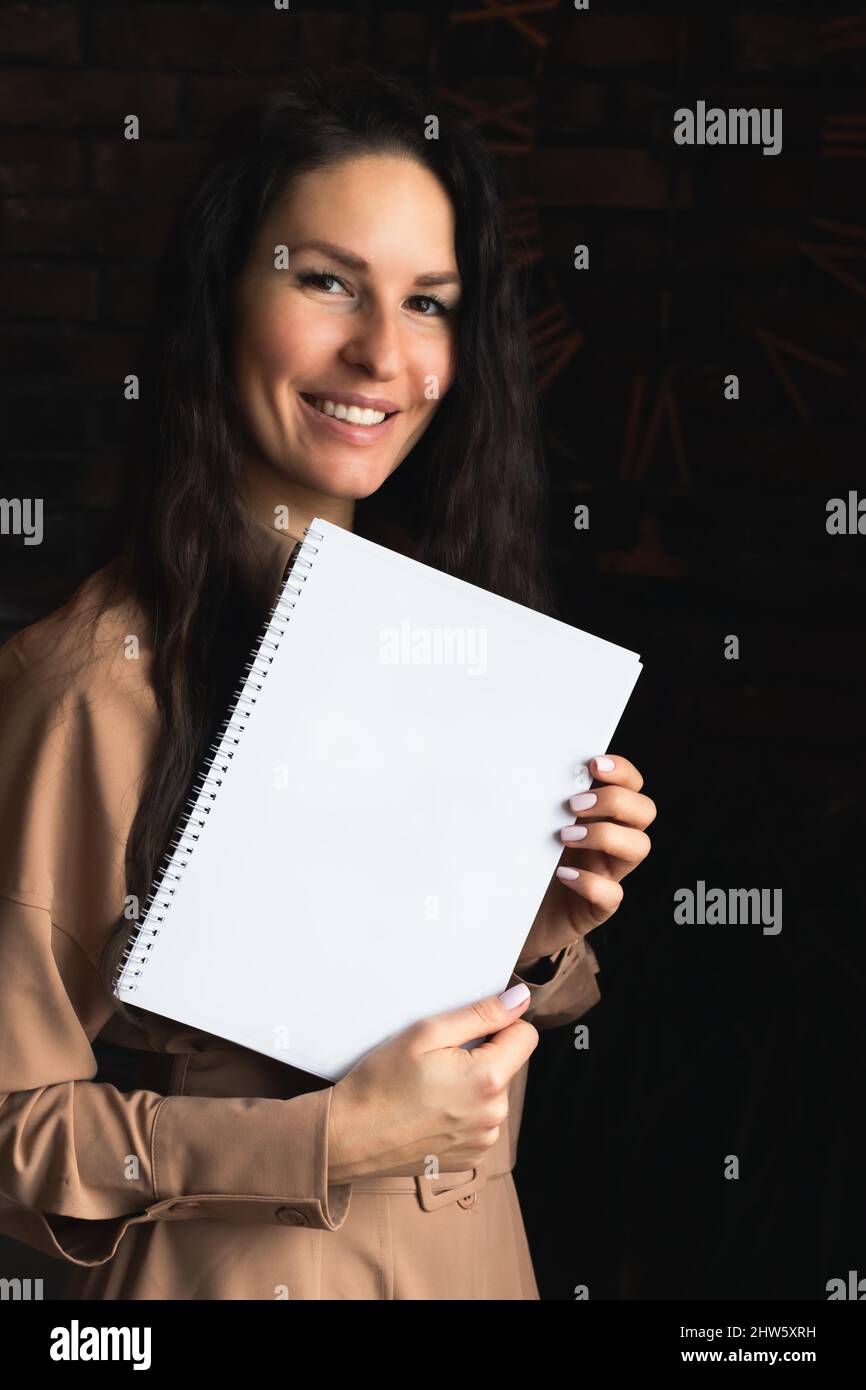Eine attraktive Brünette Frau mit Dokumenten. Vorderansicht. Vertikales Foto. Speicherplatz kopieren. Für Text platzieren. Präsentation und Verkaufskonzept. Stockfoto