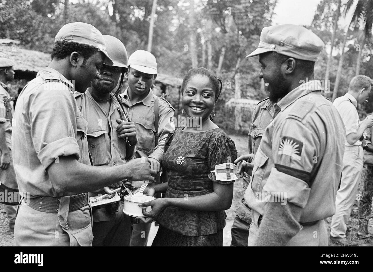 Biafraner Soldaten haben hier während des Biafraner Konflikts am 11.. Juni 1968 Lebensmittel genossen, die von einem Helfer in Besitz gehalten wurden. Der nigeranische Bürgerkrieg, auch bekannt als Biafrankrieg, dauerte zweieinhalb Jahre, vom 6. Juli 1967 bis zum 15. Januar 1970, und wurde gekämpft, um der Abspaltung von Biafra von Nigeria entgegenzuwirken. Die indigenen Igbo-Bewohner von Biafra fühlten sich nach der Unabhängigkeit von Großbritannien nicht mehr mit der nordeuropäischen Bundesregierung koexistieren können. Politische, wirtschaftliche, ethnische, kulturelle und religiöse Spannungen kochten schließlich nach dem Militärputsch von 1966, der, in einen Bürgerkrieg über Stockfoto
