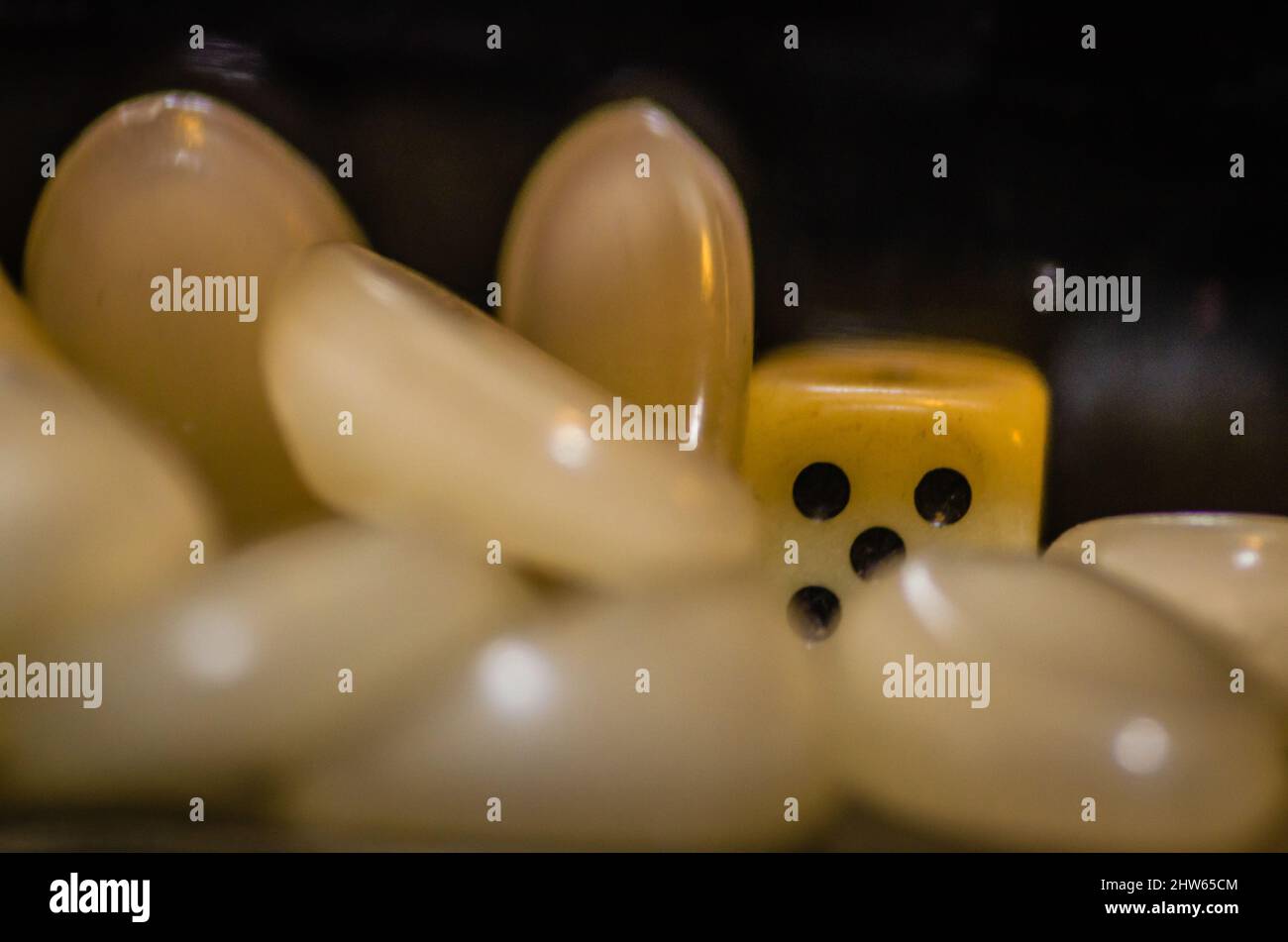 Weißer Iambic-Würfel aus Kunststoff in einer Glasflasche, umgeben von Kunststoffsteinen. Stockfoto