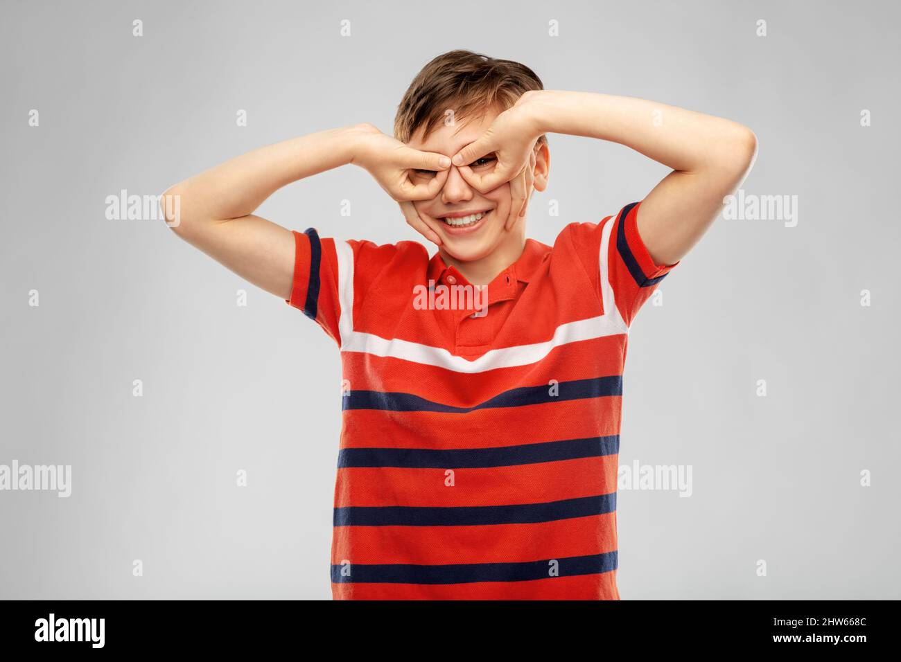 Glücklich lächelnder Junge, der durch die Fingerbrille schaut Stockfoto