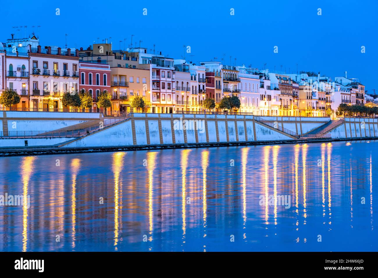Stadtviertel Triana am Ufer des Flusses Guadalquivir in der Abenddämmerung, Sevilla, Andalusien, Spanien | Triana-Viertel am Guadalquivir b Stockfoto