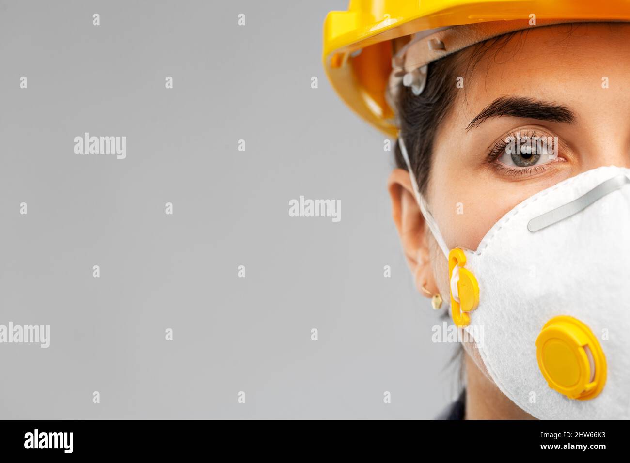 Arbeiterin oder Baumeisterin in Helm und Atemschutzmaske Stockfoto