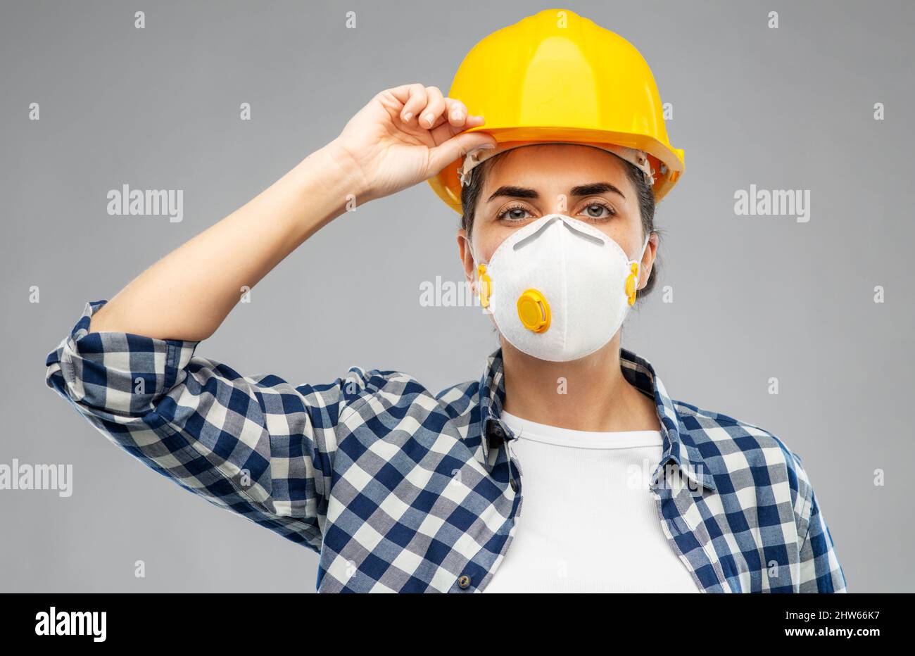 Arbeiterin oder Baumeisterin in Helm und Atemschutzmaske Stockfoto