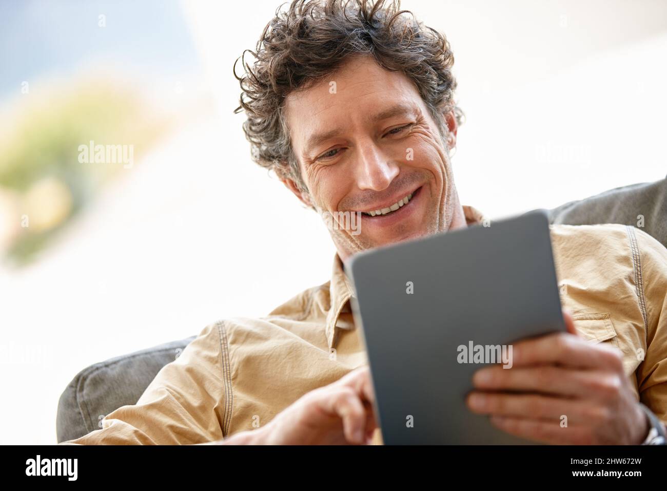 Das Surfen im Internet war noch nie so schnell. Aufnahme eines reifen Mannes, der zu Hause ein digitales Tablet auf dem Sofa benutzt. Stockfoto