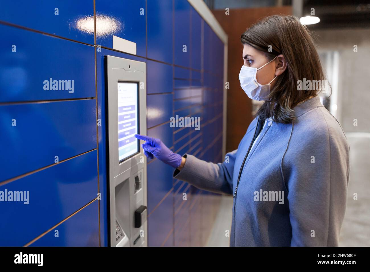 Frau in Maske am Paketautomaten Stockfoto