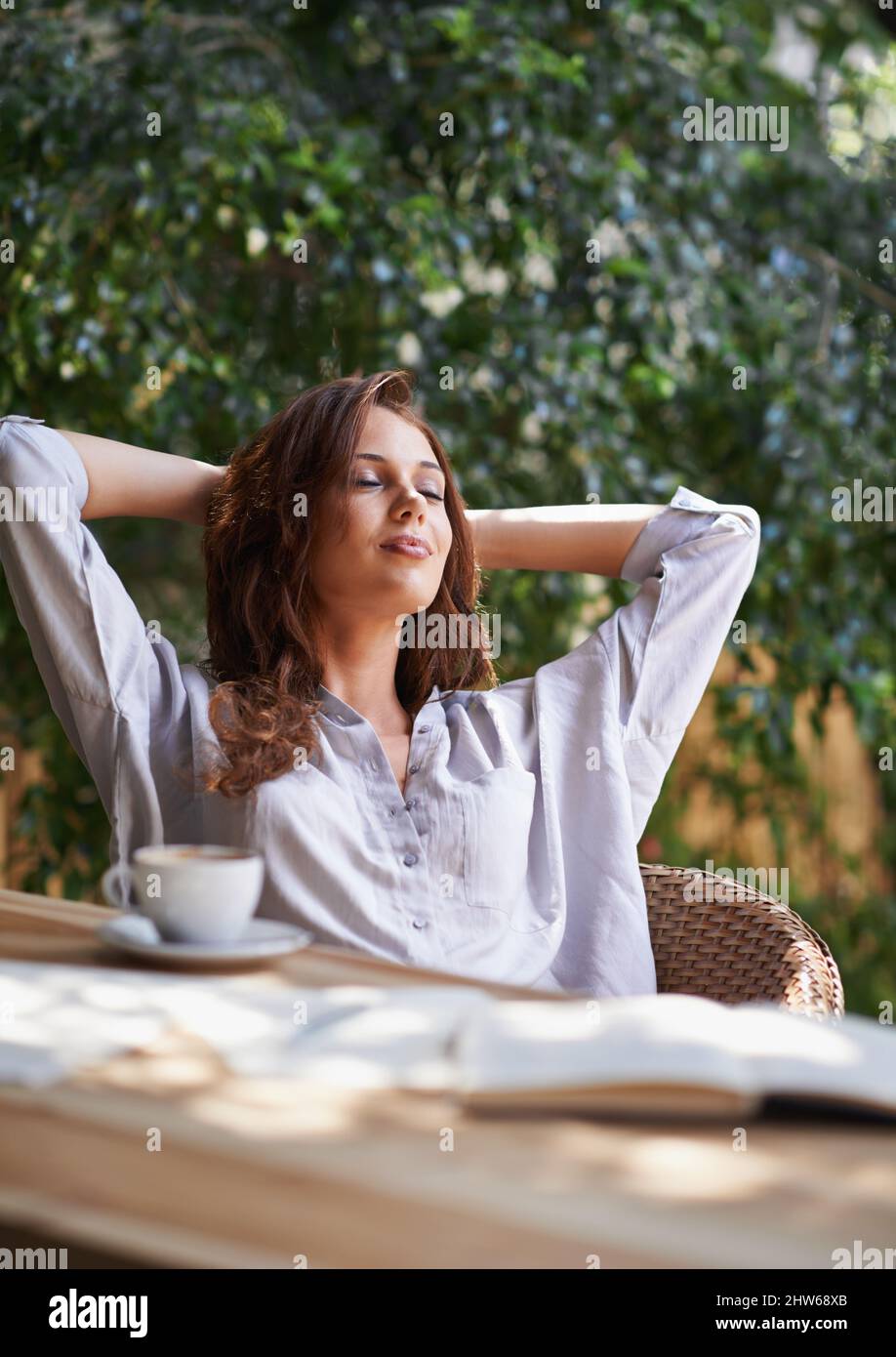 Sich etwas Zeit nehmen, um sich in der Sonne zu entspannen. Eine kurze Aufnahme einer attraktiven jungen Schriftstellerin, die eine Pause im Freien macht. Stockfoto