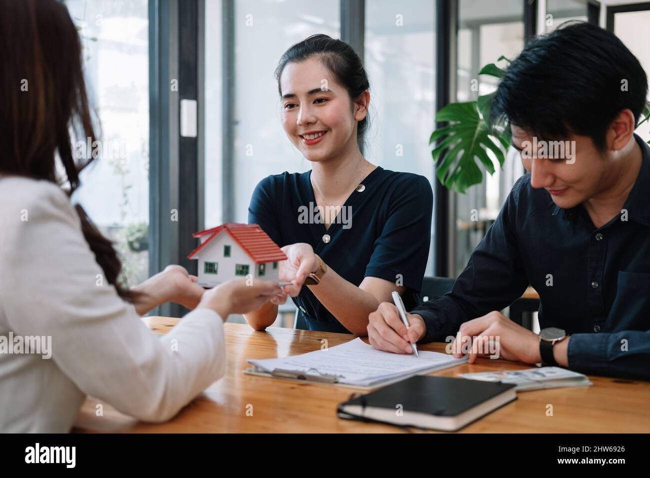 Immobilienmakler bieten Hand für Kunden unterzeichnen Vertrag Unterzeichnung für Kauf oder Verkauf Haus. Happy Asian paar Unterzeichnung eines Vertrags zusammen bei Stockfoto